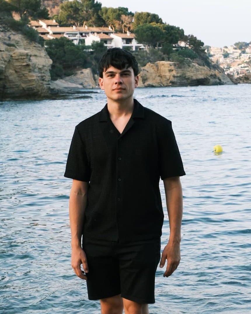Eduard, founder of OhMyClient, standing on the rocks by the sea in Spain